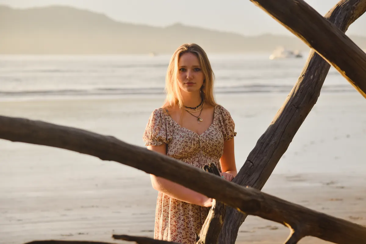 Young woman framed by driftwood logs on a beach
