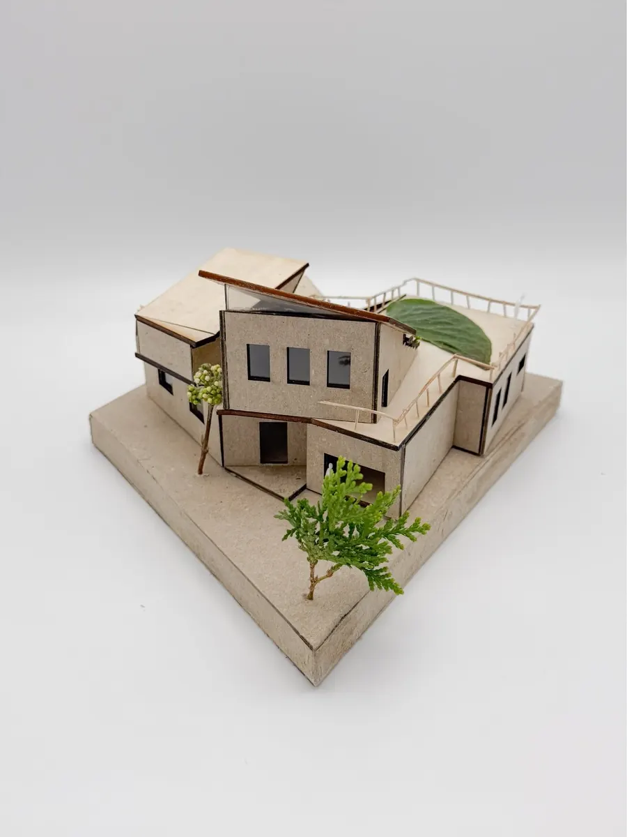 Wooden model of a two-story house with a curved green roof