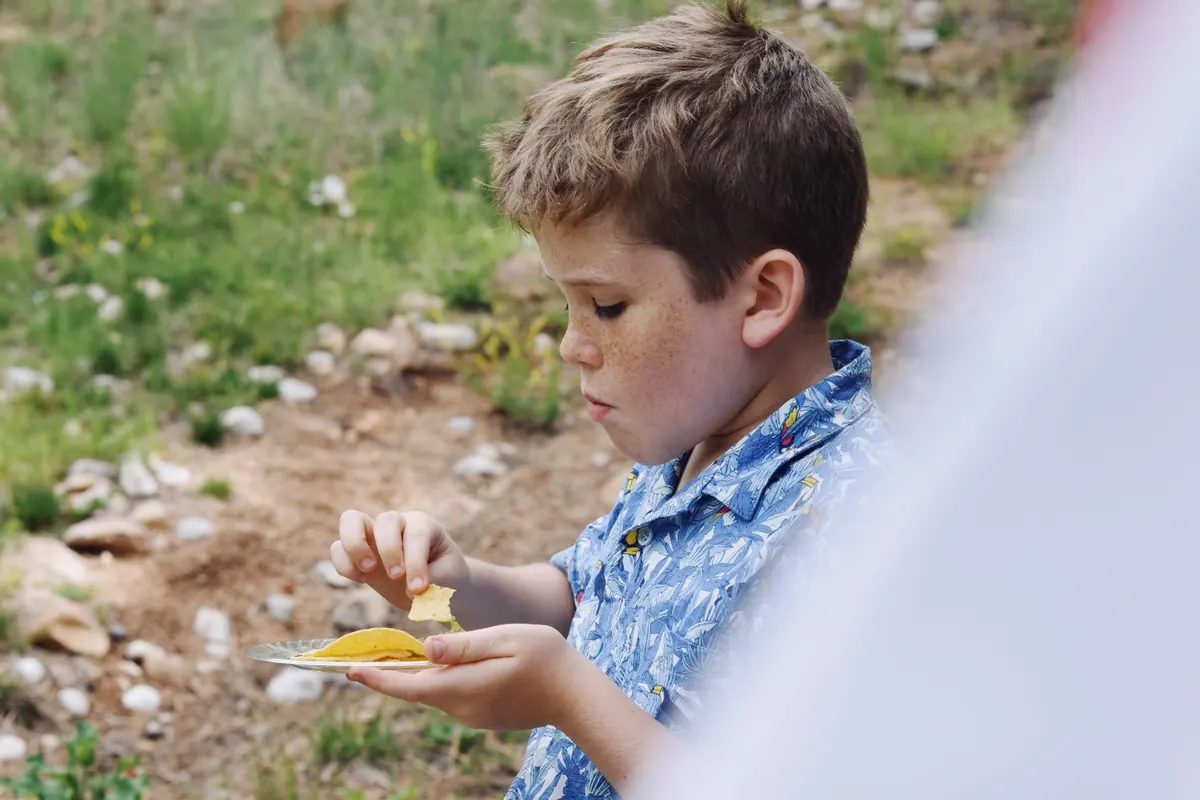 Young boy eating chips outdoors